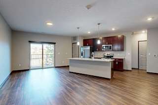 A modern kitchen with wooden cabinets, granite counters, a large central island, a pantry, and stainless steel appliances.