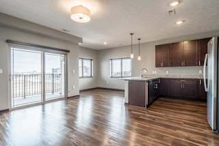 View from living room of kitchen and dining room with hardwood-style floors and balcony at 360 at Jordan West best new apartments West Des Moines IA 50266