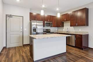 A kitchen with dark wood cabinets, granite countertops, and stainless steel appliances.