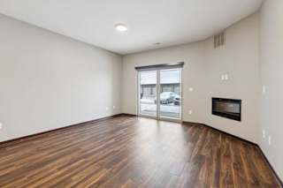 A living room with hardwood-style flooring, an electric fireplace, and a sliding glass door to a patio.