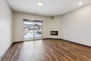 A living room with hardwood-style flooring, an electric fireplace, and a sliding glass door to a patio.