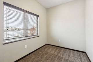 A carpeted den space with a large window and several outlets.