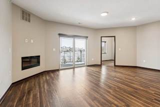 A living room with hardwood-style flooring, an electric fireplace, and a sliding glass door to a balcony.