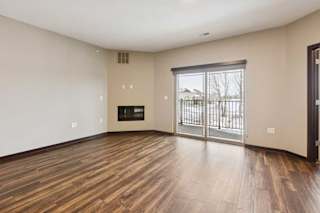 A living room with hardwood-style flooring, an electric fireplace, and a sliding glass door to a balcony.