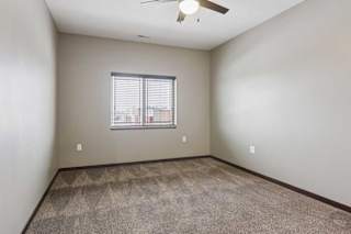 A carpeted bedroom with a ceiling fan and a window.