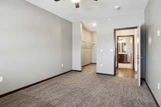 A carpeted bedroom with a ceiling fan and an open walk-in closet.