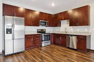A kitchen with dark wood cabinets, granite countertops, and stainless steel appliances.