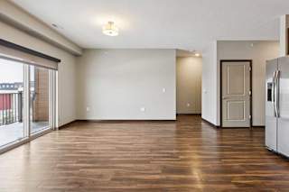 A living room with hardwood-style flooring and a sliding glass door to a balcony.