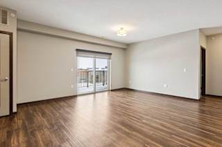 A living room with hardwood-style flooring and a sliding glass door to a balcony