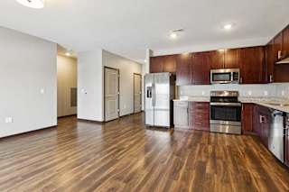 A kitchen with dark wood cabinets, granite countertops, and stainless steel appliances.