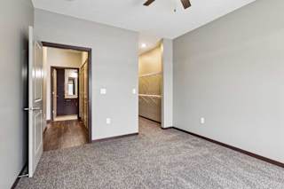 A carpeted bedroom with a ceiling fan and an open walk-in closet.