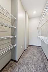 An oversized walk-in closet with several built-in wire shelves.