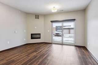 A living room with hardwood-style flooring, an electric fireplace, and a sliding glass door to a patio.