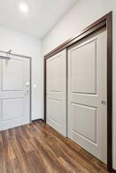 A hallway with a double-door closet and the front door at the end.