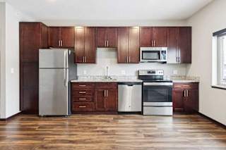 A kitchen with dark wood cabinets, granite countertops, and stainless steel appliances.