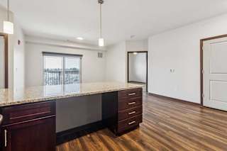 A kitchen with dark wooden cabinets in front of a spacious living room.