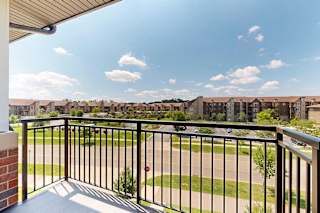 A balcony with a metal railing, overlooking the neighborhood.
