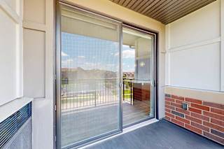 A balcony with a sliding glass door and a screen door.