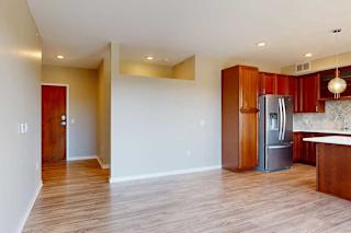 A living room with hardwood-style flooring, and a view of the front entryway.