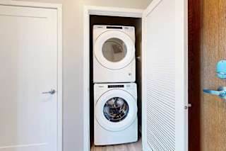 A laundry closet in the front entryway with a stacked, front-loading washer and dryer.