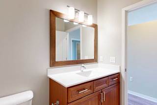 A bathroom with a white quartz vanity sink, an oversized mirror, and overhead lighting.