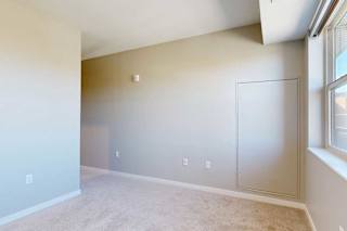 A carpeted bedroom with a large window.