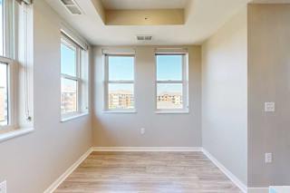 A dining area with several large windows and hardwood-style flooring.