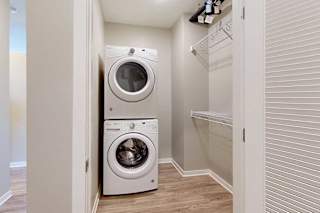 A laundry room with a stacked washer and dryer, and built-in wire shelves.