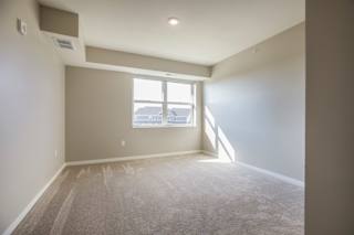 A bedroom with a window and carpeted floor.
