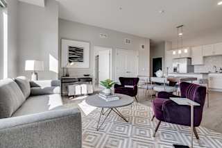 Furnished living room with high ceilings looking into the kitchen at Aspire at CityPlace Woodbury MN 55125