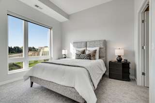 Furnished bedroom with high ceiling, large window and connected bathroom