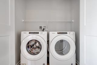 Side by side front loader washer and dryer in a laundry closet in two bedroom luxury apartment Woodbury MN 55125