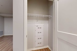 A white closet with a shelf and a white door.