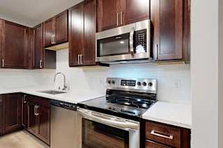 A modern kitchen with dark wood cabinets and stainless steel appliances.