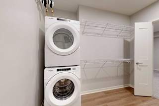 Two washing machines are stacked on top of each other in a laundry room.
