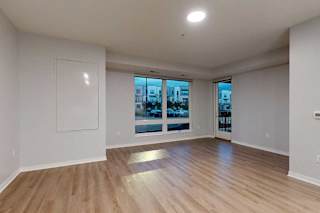 A spacious room with wooden flooring and a large window overlooking a cityscape.