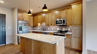 Modern apartment kitchen with a large island, wood cabinetry, and stainless steel appliances.