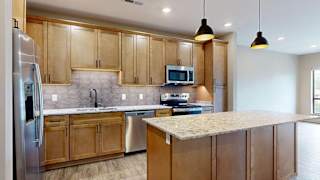 Modern apartment kitchen with a large island, wood cabinetry, and stainless steel appliances.