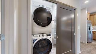 Apartment laundry closet with a stacked washer and dryer next to the kitchen.