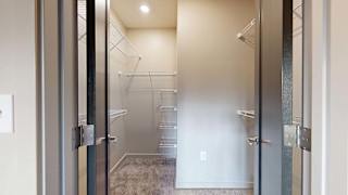 Walk-in apartment closet with built-in wire shelving and carpeted flooring.