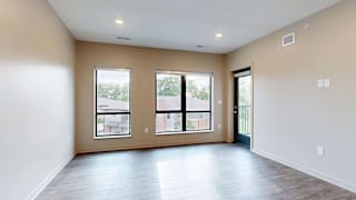 Bright apartment living area with wood-style flooring, large windows, and a private balcony.