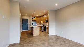 Spacious apartment living area with wood-style flooring and an open kitchen with an island.