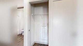 a hallway coat closet with a built-in wire shelf