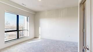 a bedroom with carpeted flooring and a window looking out to a balcony
