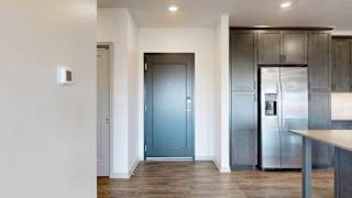 a grey front door next to a modern kitchen with dark cabinets and stainless steel appliances