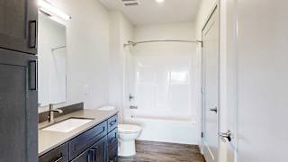 a bathroom with a dark cabinet quartz vanity sink and a combo shower tub