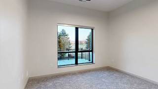 a bedroom with a large window overlooking a patio and trees