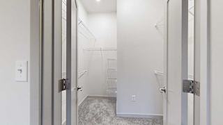 an L-shaped walk-in closet with build-in shelving and hanging space