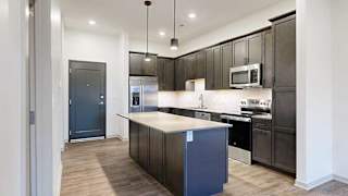 a modern kitchen with dark wood cabinets and a central island next to a front door