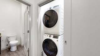 a white stackable washing machine and dryer in a laundry room next to a bathroom